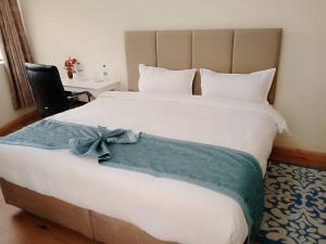 MweigaAberdare Juniper Green Gardens Resort的卧室里有一张白色的大床和一张桌子