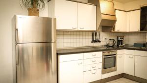 a kitchen with white cabinets and a stainless steel refrigerator at Gemütliches Apartment in Bad Berneck in Bad Berneck im Fichtelgebirge