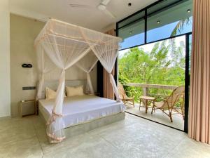 a bedroom with a canopy bed and a balcony at Lotus Surf House in Midigama East