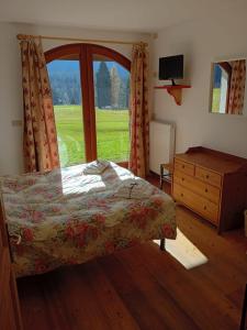a bedroom with a bed and a large window at Oberthaler Hotel in Sappada
