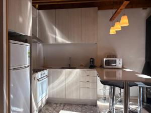 een keuken met witte apparatuur en een tafel met een magnetron bij Chimenea y piscina-Dúplex perfecto para todo el año - Herbasabina 4 in Pla de l'Ermita