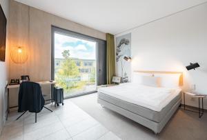 a bedroom with a large bed and a large window at gambino hotel CINCINNATI in Munich
