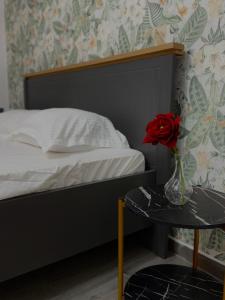克拉约瓦Petra's的一间卧室配有一张床,一个花瓶上放着玫瑰花