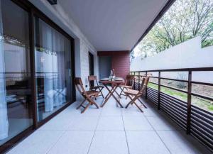 einen Balkon mit einem Tisch und Stühlen sowie großen Fenstern in der Unterkunft Clos des chênes - Terrasse Parking Tram à 1 min in Castelnau-le-Lez + 7 Fotos