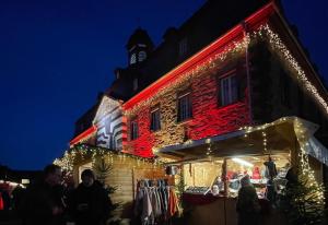 un bâtiment recouvert de lumières de Noël avec une tour d'horloge dans l'établissement Paradies in der Vulkaneifel mit Panorama-Blick, à Burgbrohl