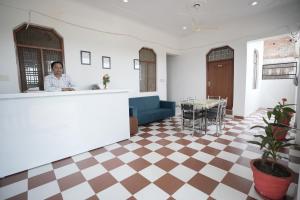 a woman standing at a counter in a room with a checkered floor at Parkview Hotel in Khajurāho