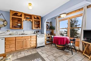 德卢斯Great Lakes Suite InnOnGitcheGumee的厨房配有木制橱柜、桌子和窗户。