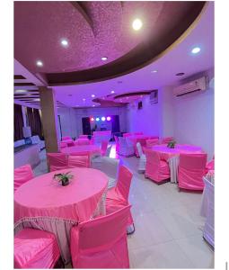 a room with pink tables and chairs with purple lighting at Hotel Aero Home in Behror