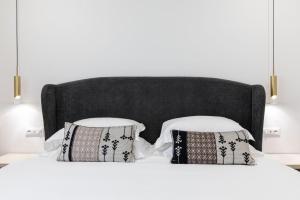 a bedroom with a white bed with two pillows at Feel Boutique Rooms in Oristano