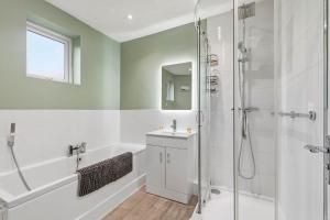 un bagno bianco con doccia e lavandino di Seven Space - Church Close a Coltishall