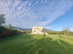 a house in the middle of a grassy field with a cloudy sky at Green Galini Villa Pelion in Káto Lekhónia