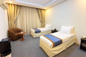 Az Zahrāʼにあるفندق درر الراشديةのベッド2台と椅子があるホテルの部屋