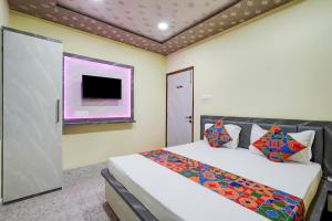 a bedroom with a bed and a tv on the wall at FabHotel Shivkashi Inn - Dasaswamedh Ghat in Varanasi