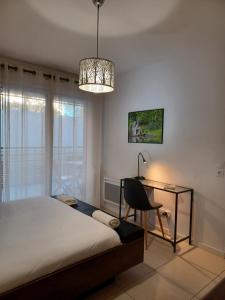 ein Schlafzimmer mit einem Bett, einem Schreibtisch und einem Kronleuchter in der Unterkunft Clos des chênes - Terrasse Parking Tram à 1 min in Castelnau-le-Lez