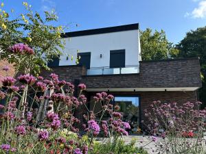 a house with a garden with pink flowers at Ferienwohnung Sonnendeck in Kranenburg