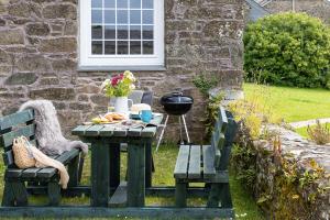 a picnic table and two benches in front of a house at Cherry Cottage in Saint Endellion
