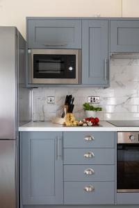 a kitchen with gray cabinets and a microwave at Cherry Cottage in Saint Endellion +20 photos