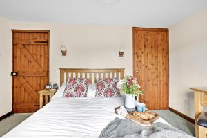 a bedroom with a white bed with wooden doors at Cherry Cottage in Saint Endellion