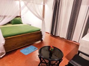 a bedroom with a bed with a table and a window at The Glown Weligama in Weligama