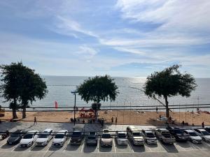 โรงแรม เซิร์ฟบีช Surf Beach Hotel في جومتين بيتش: مجموعة من السيارات تقف في موقف للسيارات بجوار الشاطئ