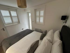 ein Schlafzimmer mit einem Bett und zwei Fenstern in der Unterkunft One Bedroom Ground Floor Flat in Whitstable in Whitstable