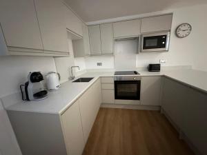 eine Küche mit weißen Schränken und einer Uhr an der Wand in der Unterkunft One Bedroom Ground Floor Flat in Whitstable in Whitstable