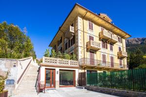 een groot geel gebouw met een hek en een trap bij L'Atelier du Temps - Maison Ida in Courmayeur