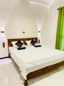 a bedroom with a large white bed with green curtains at THE PRASINOS villa & resort in Habaraduwa