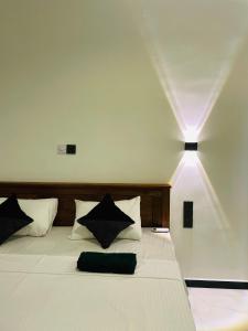 a bedroom with a white bed with black pillows at THE PRASINOS villa & resort in Habaraduwa +13 photos