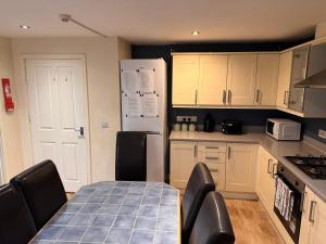 Una cocina con mesa y sillas y un refrigerador. en Valley View Guest House, en Newcastle-under-Lyme