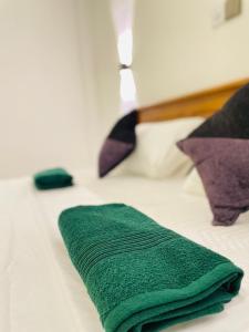 - une serviette verte assise au-dessus du lit dans l'établissement THE PRASINOS villa & resort, à Habaraduwa Central