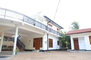 a large white building with a balcony on top at Naren Guest House in Kallady