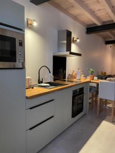 une cuisine avec des armoires blanches et un comptoir dans l'établissement Petite maison au centre de Mirepoix, à Mirepoix