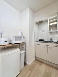 Ikeda Ueno 401 Quad room في طوكيو: مطبخ صغير مع دواليب بيضاء وميكرويف +10 صور