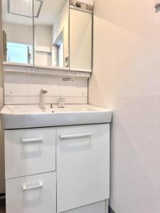 ein weißes Badezimmer mit Waschbecken und Spiegel in der Unterkunft Ikeda Ueno 501 Quad room Room in Tokio