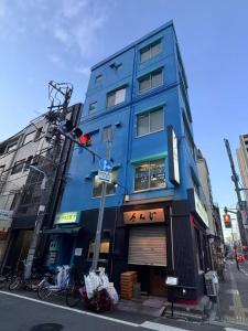 ein blaues Gebäude an einer Stadtstraße mit einer Ampel in der Unterkunft Ikeda Ueno 501 Quad room Room in Tokio