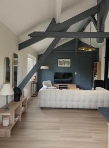 a living room with a white couch and a tv at Chalet de 95m2 au cœur du Pays d'Auge, en Normandie avec Piscine et Jacuzzi in Les Champeaux