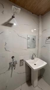 een witte badkamer met een wastafel en een spiegel bij Himaja Retreat in Manāli