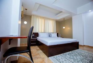 una camera da letto con un letto, una scrivania e una sedia di Tima Residence a Dar es Salaam