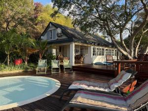 a house with a deck with chairs and a swimming pool at Villa Abre de l'intendance avec vue mer et piscine à Boucan Canot in Saint-Paul