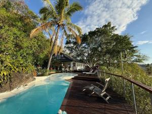 a swimming pool with a chair and a palm tree at Villa Abre de l'intendance avec vue mer et piscine à Boucan Canot in Saint-Paul