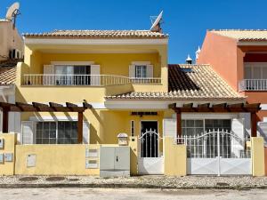 ein gelbes Haus mit weißen Türen und einem Balkon in der Unterkunft V4 moderno com Piscina - Burgau in Burgau
