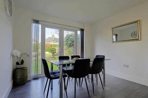 a dining room with a glass table and black chairs at Comfortable 3-Bed Home - Driveway Parking in Long Eaton
