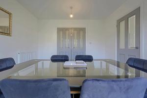 a conference room with a glass table and blue chairs at Comfortable 3-Bed Home - Driveway Parking in Long Eaton