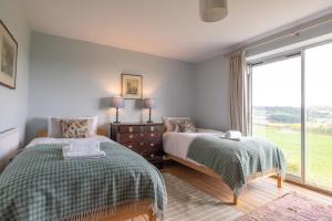a bedroom with two beds and a window at Greengates Nature Filled Countryside Escape 