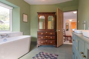 a bathroom with a tub and a sink and a mirror at Greengates Nature Filled Countryside Escape  +117 photos