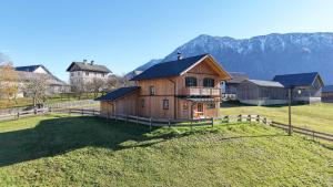 a large wooden house in a field with a fence at Ferienhaus Bergmann in Bad Aussee