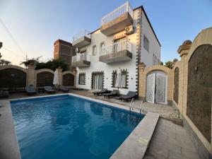 a villa with a swimming pool in front of a house at Twins Villa Luxor in Luxor