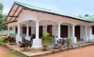 a white house with potted plants in front of it at First House Mihintale in Mihintale