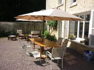 einen Holztisch und Stühle mit Sonnenschirm in der Unterkunft La Roseliére in Bazenville + 4 Fotos